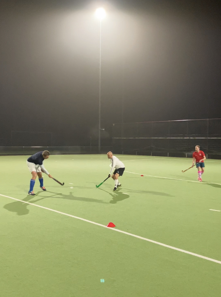 Foto van enkele spelers die aan het spelen zijn op een hockeyveld.